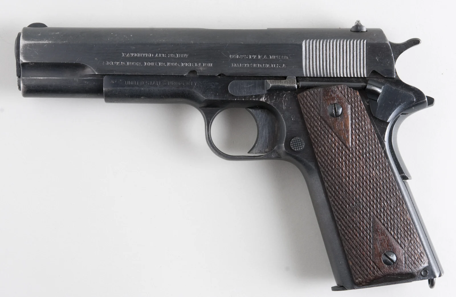 Left-side view of a historical Colt M1911 with walnut grips.
